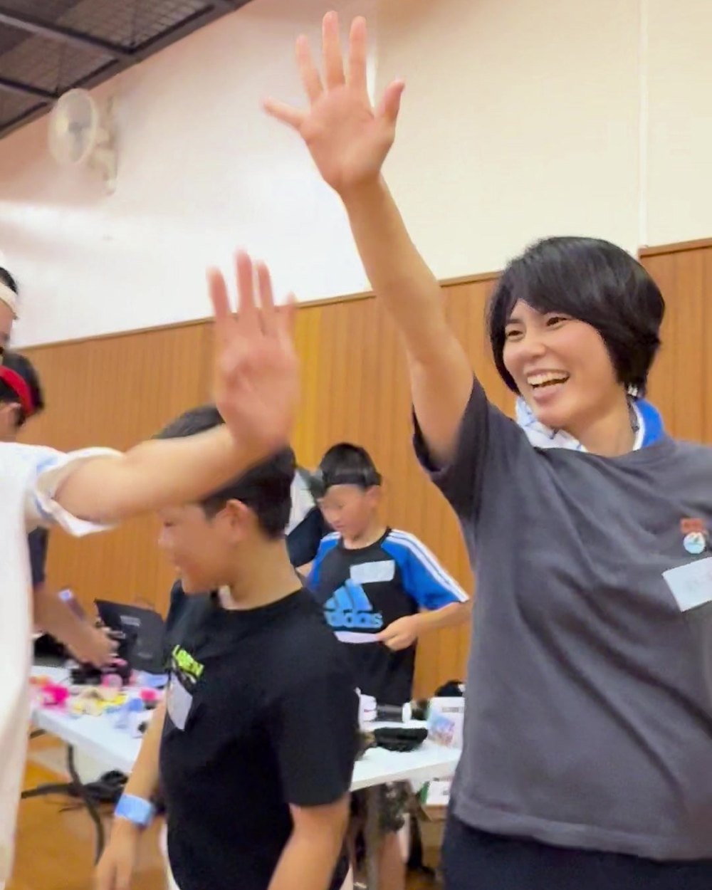 試合後、参加者同士で手を上げてハイタッチする様子。奥で女性が笑っている